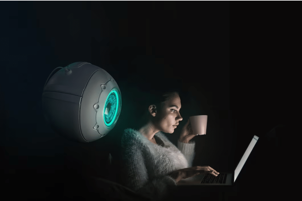 Women at computer being watched by a big robotic eye