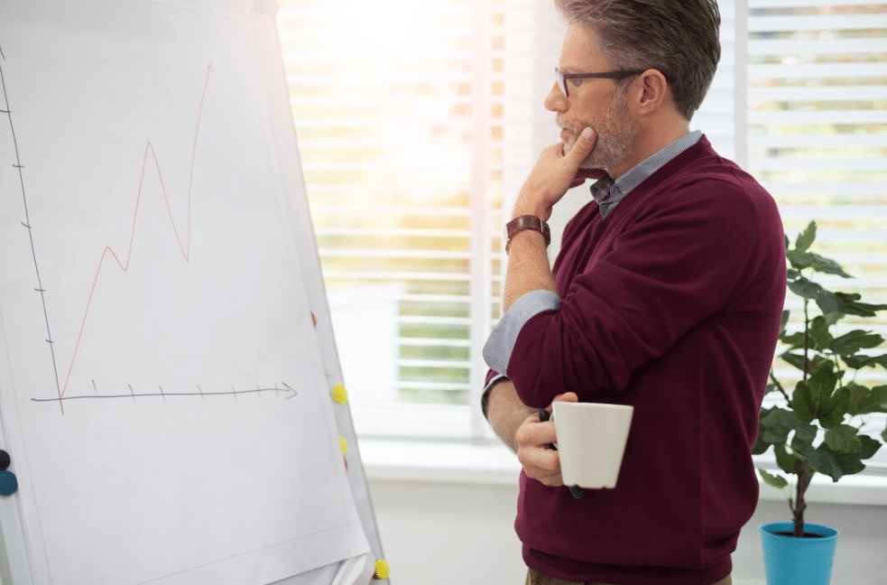 A man looking at a graph and thinking representing a data-driven thinker, one of the characteristics of a sales enablement strategy professional
