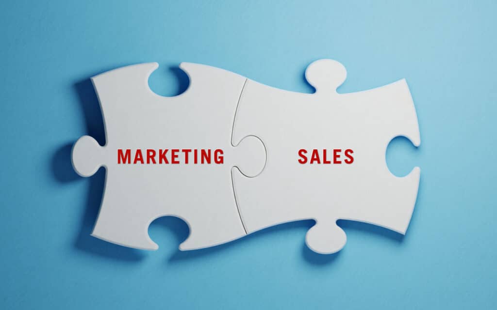 White  jigsaw puzzles on blue background. Marketing and Sales writes on jigsaw puzzle pieces. Horizontal composition with copy space. Great use for marketing concepts.